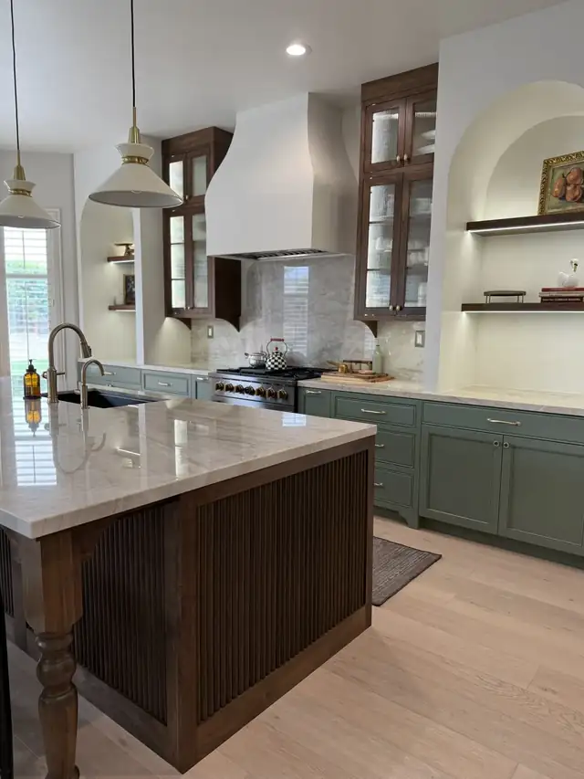 Kitchen with sage green lower cabinets, a plaster hood, arched open shelving and a walnut island with a turned leg