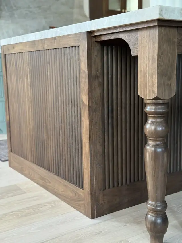 Fluted walnut kitchen island panel with a hand-turned corner leg