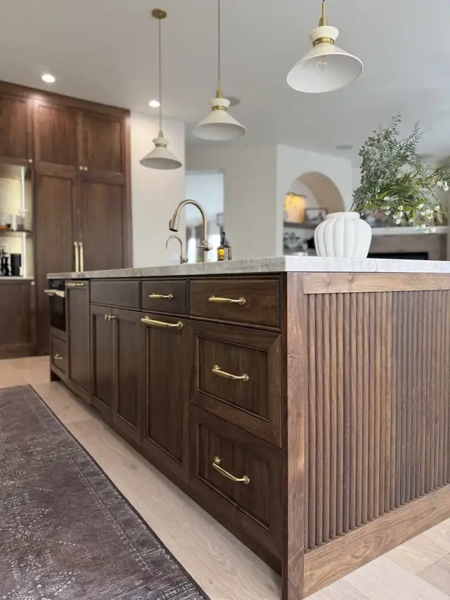 Folsom kitchen with custom walnut island, fluted end panel, brass pulls and white pendant lights